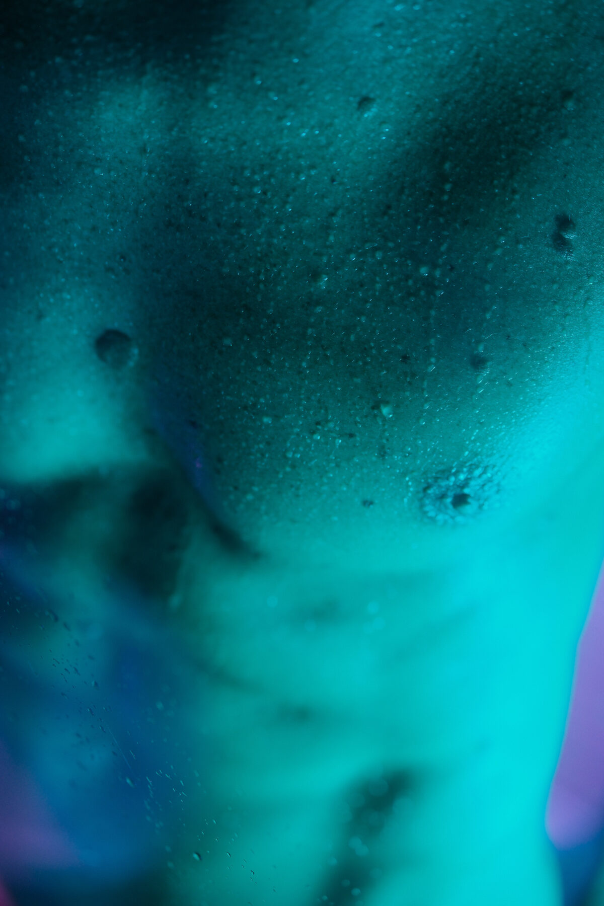 Gros plan abstrait sur la peau d'un homme, éclairage turquoise, photographie artistique