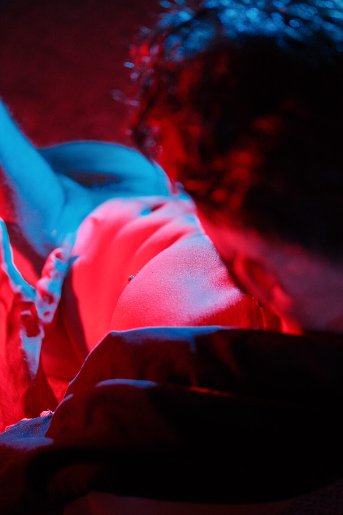 Andy allongé, corps à demi plongé dans l'ombre, lumière rouge et bleue