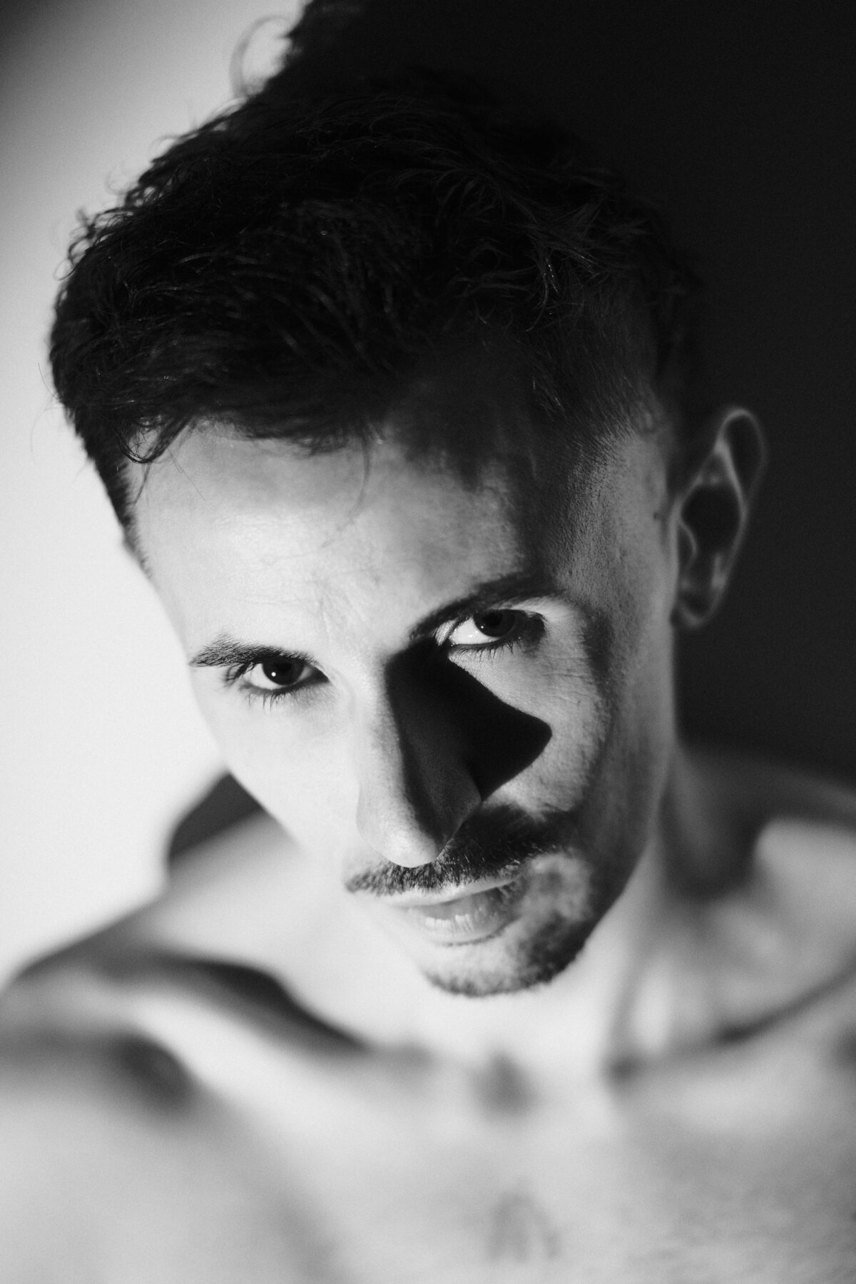 Portrait noir et blanc de Romain en contre-plongée, ombre sur le visage, clair-obscur