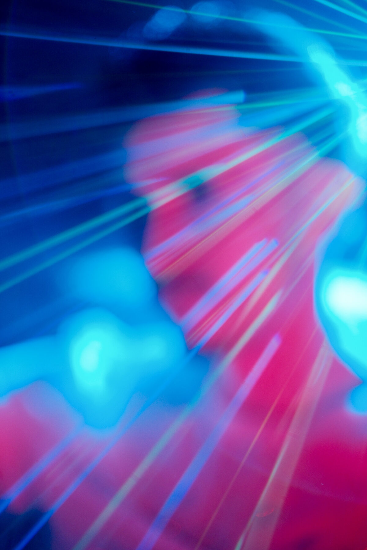 Silhouette floue de Romain derrière des faisceaux laser bleus et rouges, photo abstraite en lumière néon